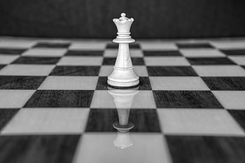 One white queen chess piece on a chess board